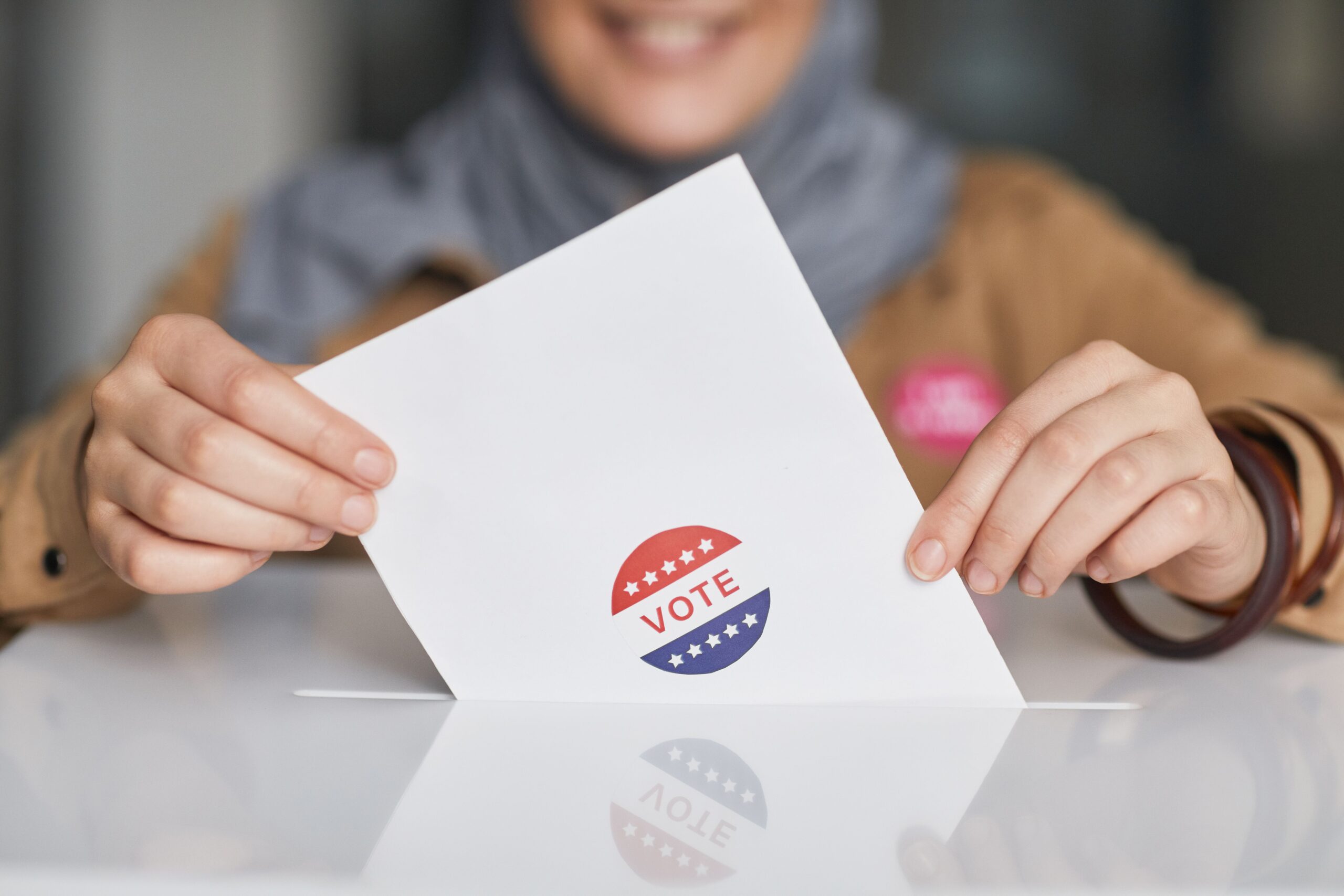 Photo of ballot held by two hands with person out of focus in the background // pexels-edmond-dantes