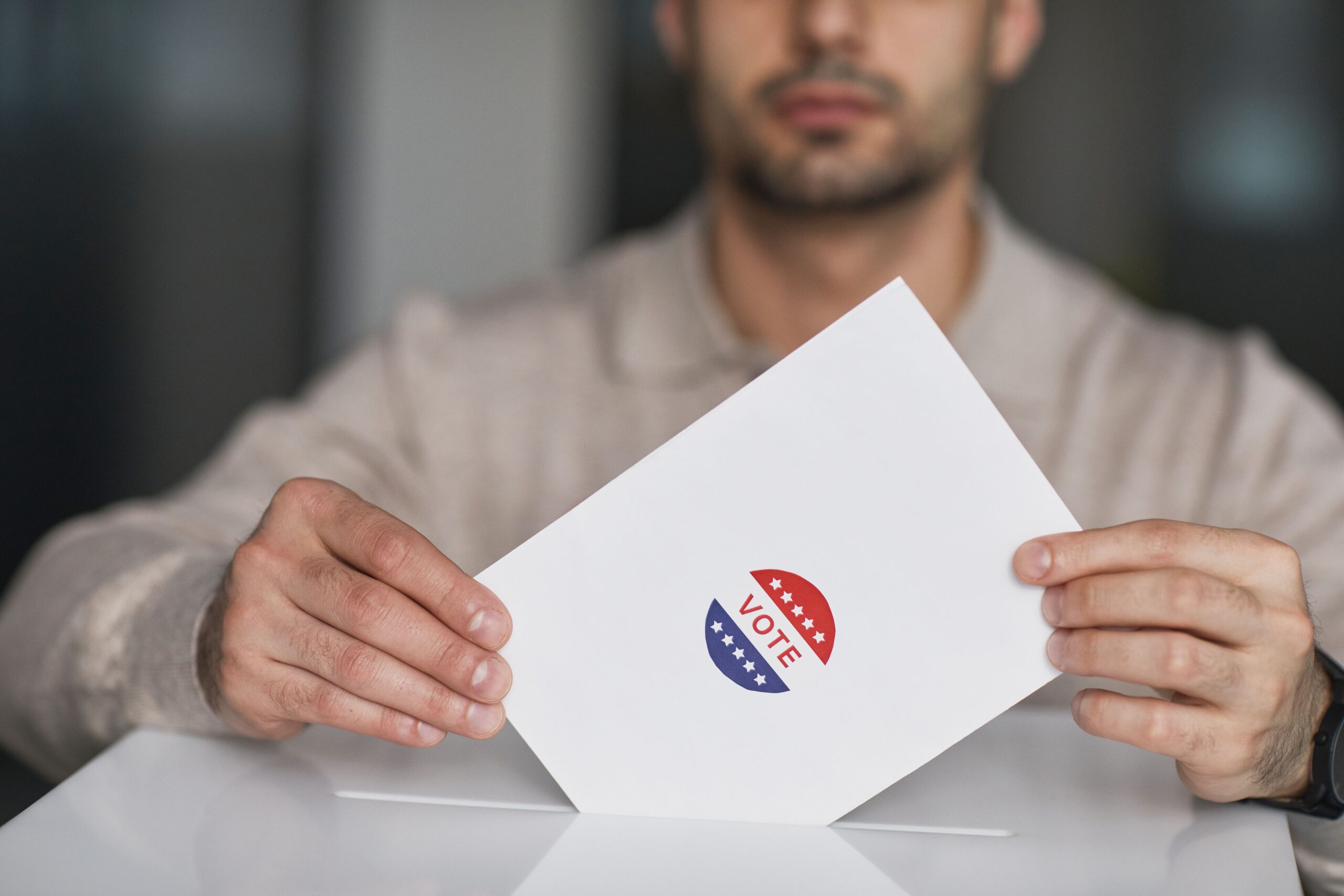 Photo of ballot held by two hands with person out of focus in the background // pexels-edmond-dantes